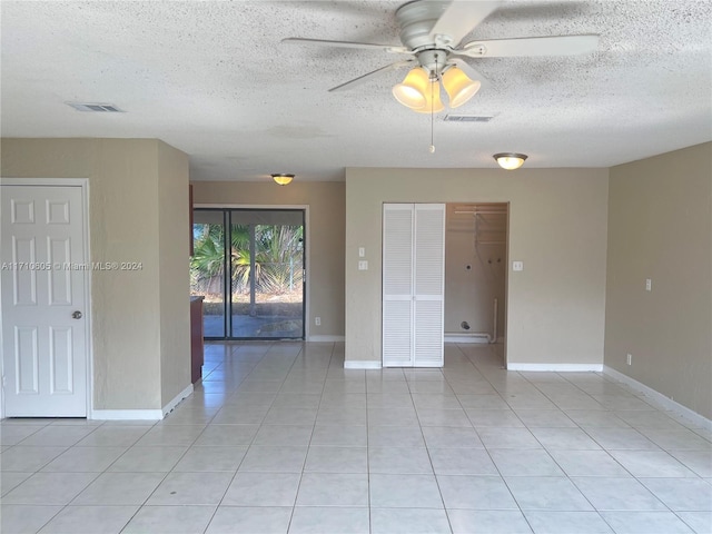 tiled spare room with a textured ceiling and ceiling fan