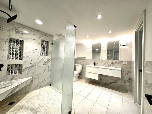 bathroom featuring walk in shower, tile patterned floors, toilet, vanity, and tile walls