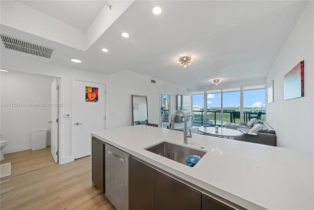 kitchen with dishwasher, expansive windows, sink, and light hardwood / wood-style flooring