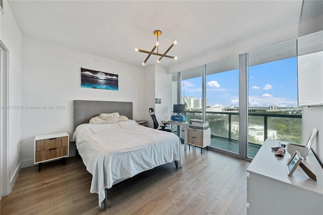 bedroom with access to exterior, hardwood / wood-style flooring, floor to ceiling windows, and a notable chandelier