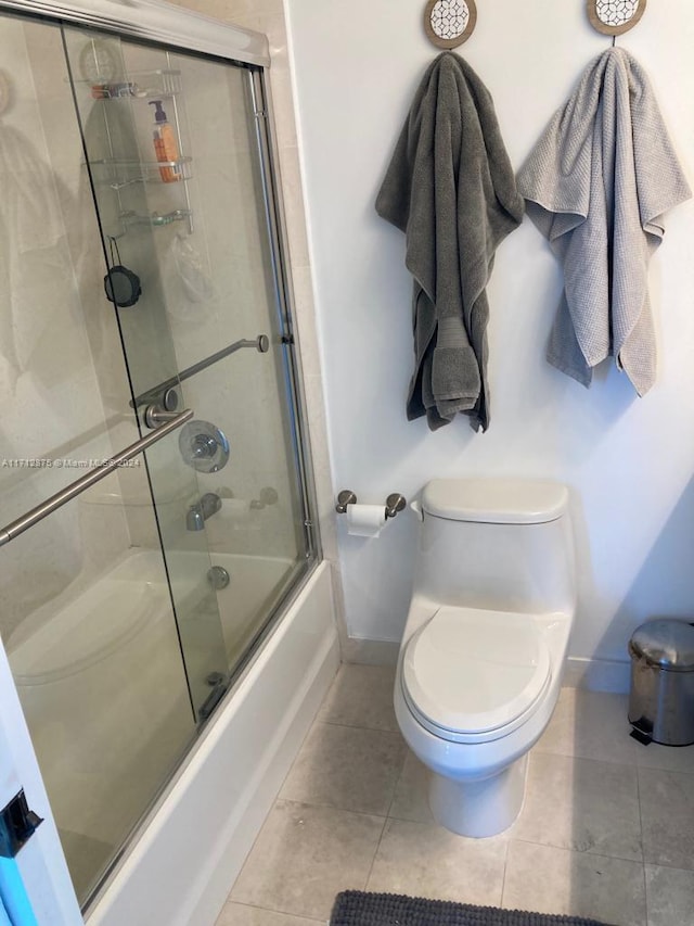 bathroom featuring tile patterned floors, toilet, and shower / bath combination with glass door