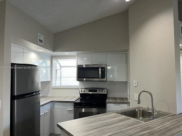 kitchen with white cabinets, decorative backsplash, sink, and stainless steel appliances