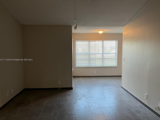 empty room with hardwood / wood-style flooring and a textured ceiling