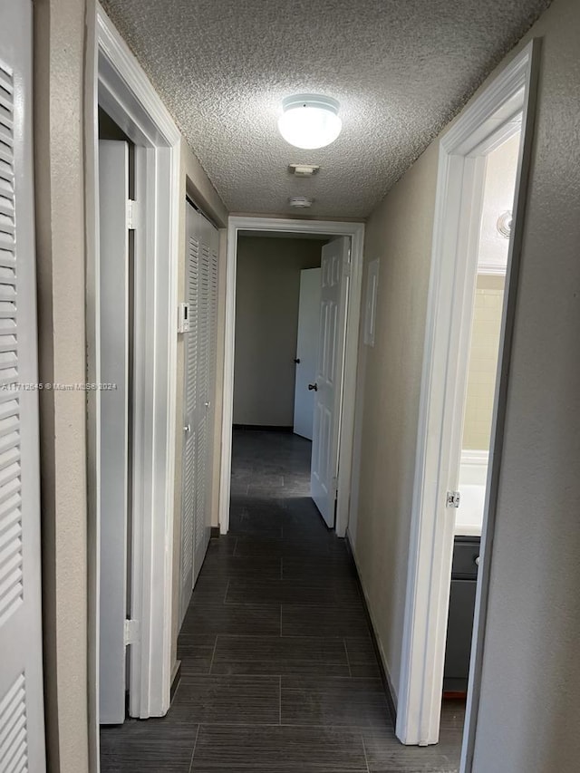 hallway featuring a textured ceiling and dark wood-type flooring