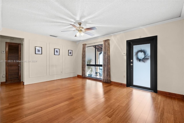 empty room with a textured ceiling, light hardwood / wood-style floors, ceiling fan, and crown molding