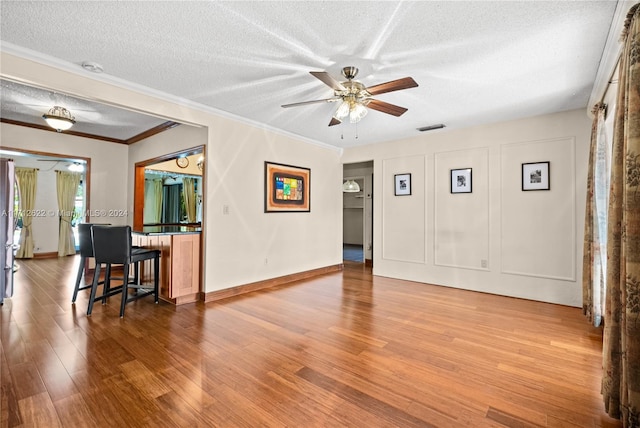 living room featuring ceiling fan, crown molding, a textured ceiling, and hardwood / wood-style flooring