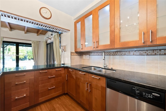 kitchen featuring dark stone counters, sink, light hardwood / wood-style flooring, stainless steel dishwasher, and beamed ceiling