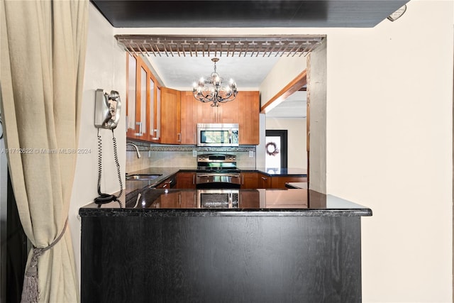 kitchen featuring hanging light fixtures, appliances with stainless steel finishes, tasteful backsplash, kitchen peninsula, and a chandelier