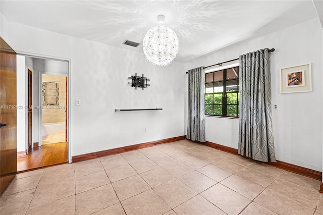 empty room featuring a chandelier and light tile patterned floors