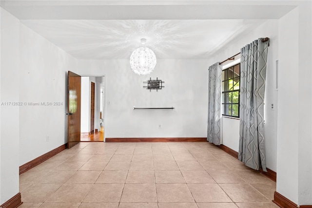 spare room featuring light tile patterned flooring and an inviting chandelier