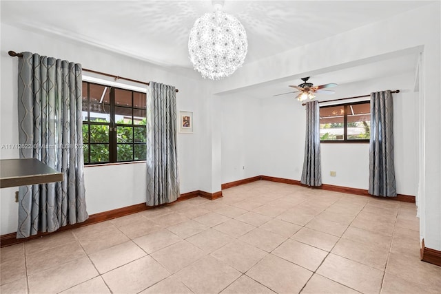 empty room with light tile patterned floors and ceiling fan with notable chandelier