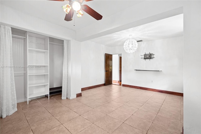 unfurnished bedroom with light tile patterned floors, ceiling fan with notable chandelier, and a closet