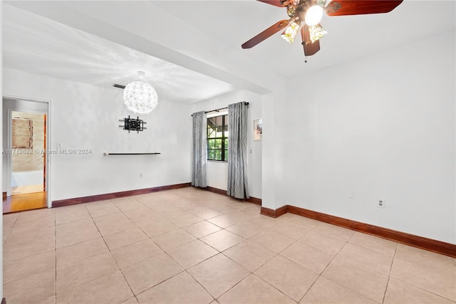 unfurnished room with light tile patterned floors and ceiling fan with notable chandelier