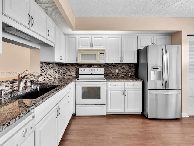 kitchen with white cabinetry, dark stone countertops, white appliances, and sink