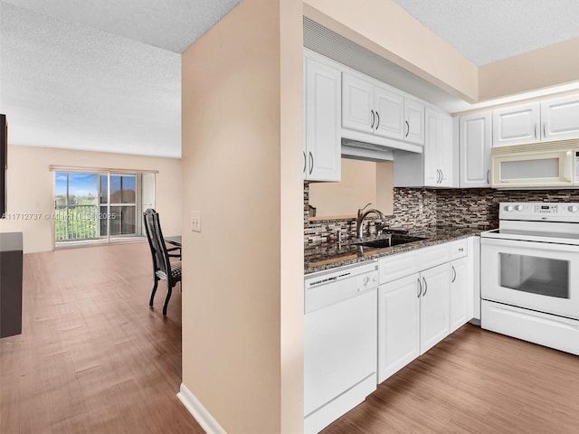 kitchen featuring sink, white cabinets, dark stone counters, and white appliances