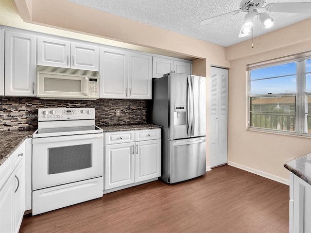 kitchen featuring ceiling fan, white cabinetry, white appliances, and dark stone counters