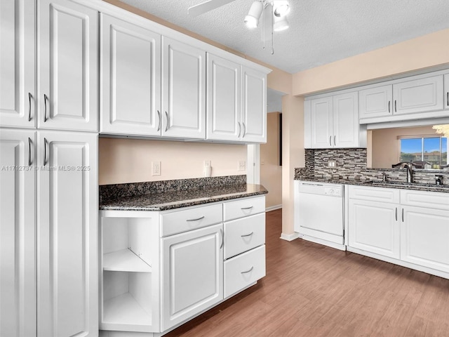 kitchen featuring dishwasher, white cabinets, sink, ceiling fan, and dark stone countertops