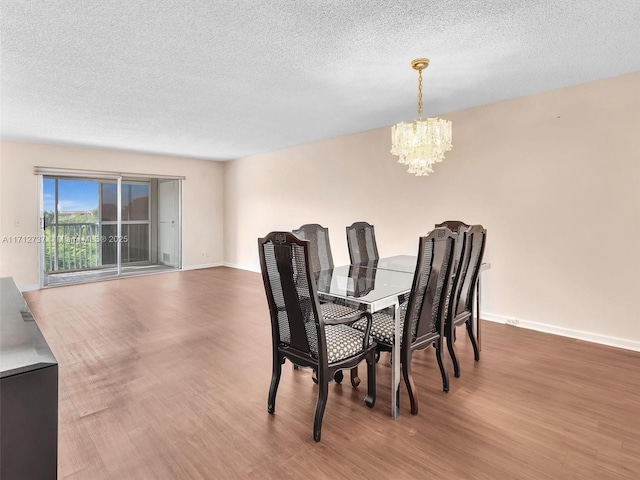 dining room with a notable chandelier, wood-type flooring, and a textured ceiling