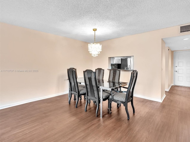 dining room with hardwood / wood-style floors, a notable chandelier, and a textured ceiling