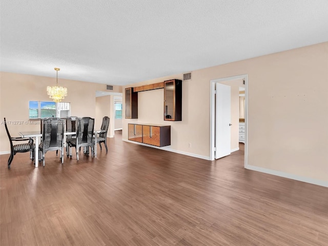 dining room featuring a textured ceiling, dark hardwood / wood-style flooring, and an inviting chandelier