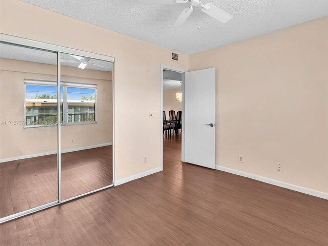 unfurnished bedroom featuring dark hardwood / wood-style flooring, a textured ceiling, a closet, and ceiling fan