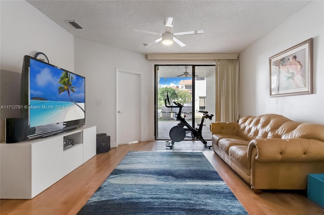 living room featuring a textured ceiling, light hardwood / wood-style flooring, and ceiling fan