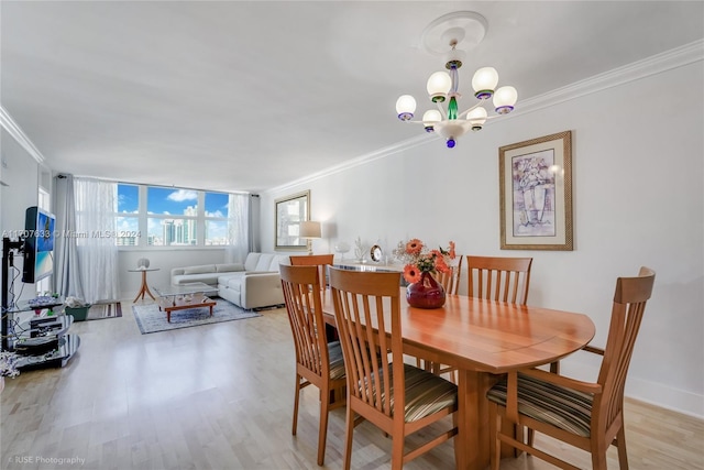 dining area featuring a notable chandelier, ornamental molding, and light hardwood / wood-style flooring