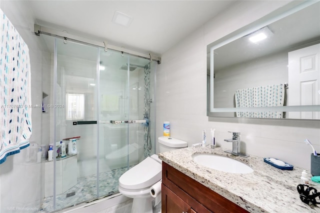 bathroom with vanity, a shower with shower door, and toilet