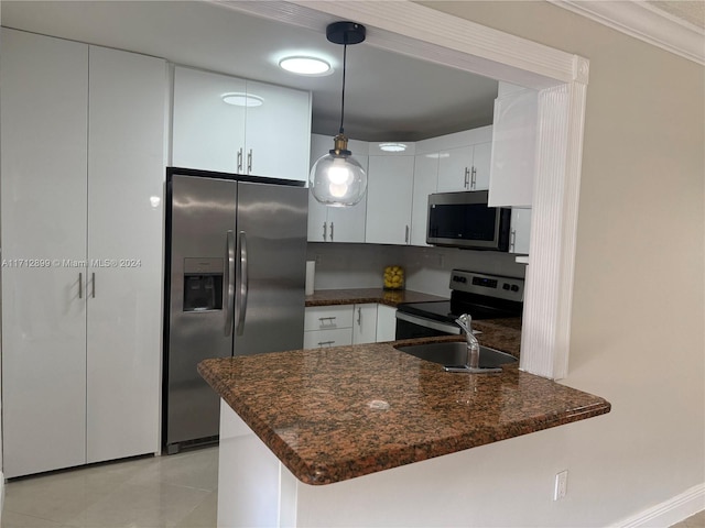 kitchen with sink, kitchen peninsula, hanging light fixtures, appliances with stainless steel finishes, and white cabinetry