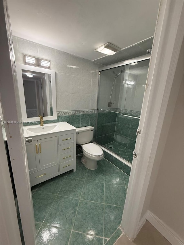 bathroom featuring tile patterned floors, an enclosed shower, tile walls, and toilet