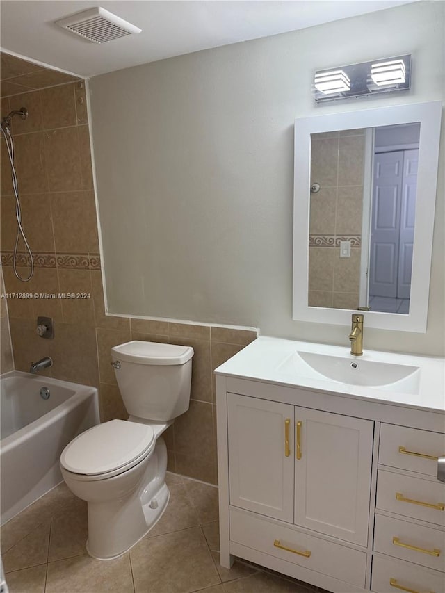 full bathroom with tiled shower / bath combo, tile patterned flooring, toilet, vanity, and tile walls