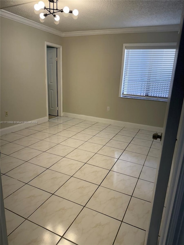 unfurnished room featuring a chandelier, a textured ceiling, ornamental molding, and light tile patterned flooring