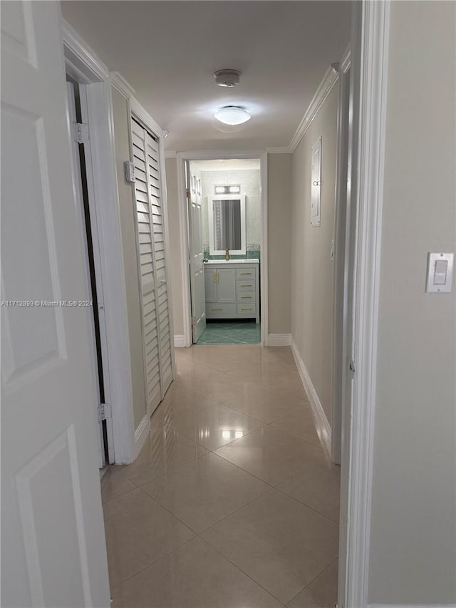 corridor with light tile patterned floors and ornamental molding