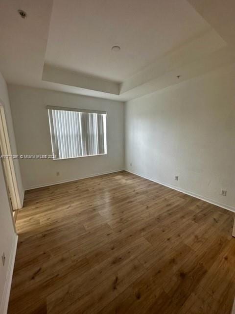 unfurnished room featuring hardwood / wood-style flooring and a raised ceiling