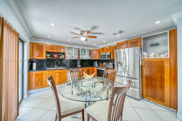 kitchen with sink, crown molding, appliances with stainless steel finishes, tasteful backsplash, and light tile patterned flooring