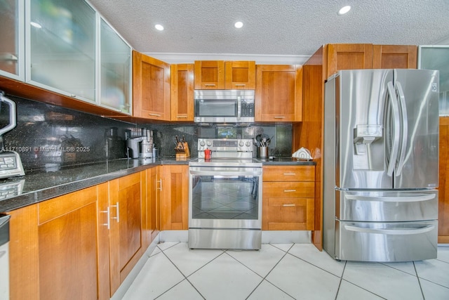 kitchen with light tile patterned floors, dark stone countertops, backsplash, stainless steel appliances, and a textured ceiling