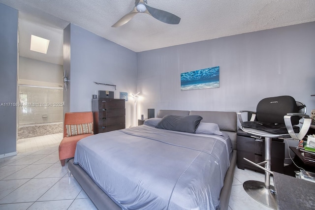 bedroom with light tile patterned floors, ensuite bath, ceiling fan, a skylight, and a textured ceiling