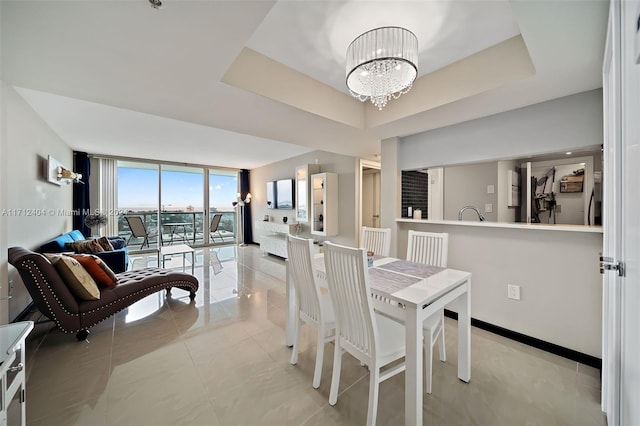 dining space with a tray ceiling, light tile patterned floors, and a notable chandelier