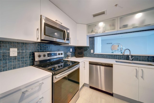 kitchen featuring white cabinetry, sink, backsplash, light tile patterned flooring, and appliances with stainless steel finishes