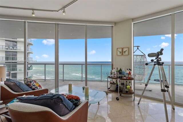 living area with expansive windows, a water view, and rail lighting