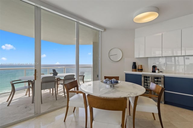 dining area with expansive windows, plenty of natural light, a water view, and wine cooler