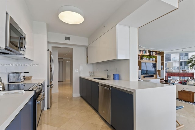 kitchen featuring white cabinets, sink, stainless steel appliances, and tasteful backsplash