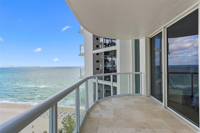 balcony with a water view and a view of the beach