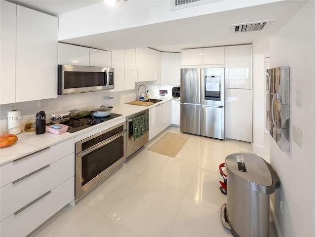 kitchen featuring visible vents, modern cabinets, a sink, white cabinetry, and appliances with stainless steel finishes