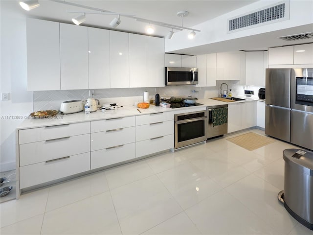 kitchen featuring visible vents, a sink, appliances with stainless steel finishes, modern cabinets, and backsplash