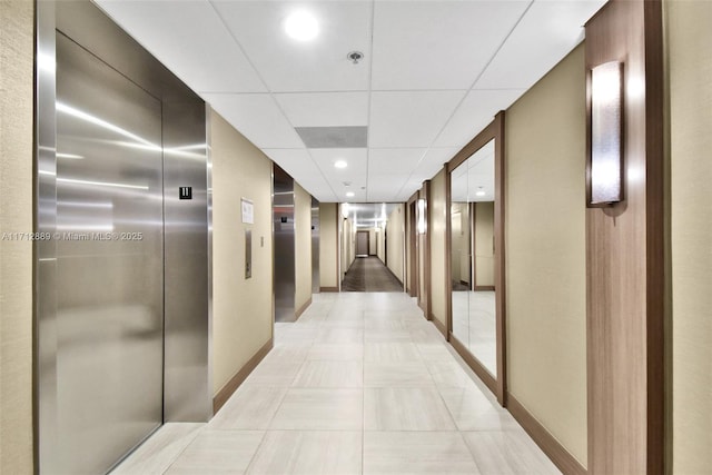 corridor featuring elevator, a drop ceiling, recessed lighting, and baseboards