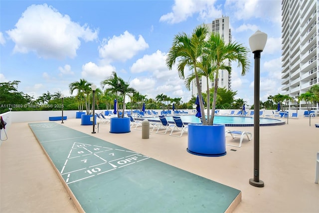 view of community with a swimming pool, shuffleboard, and a patio area