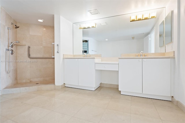 bathroom with a tile shower, tile patterned flooring, and vanity