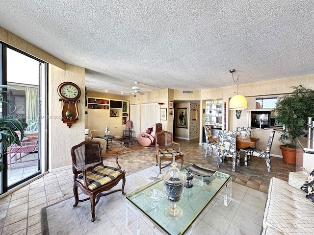 living room with ceiling fan and a textured ceiling