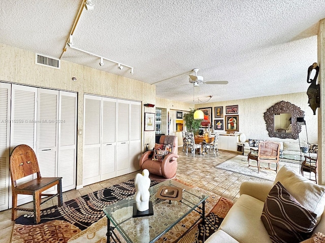 living room featuring ceiling fan, track lighting, and a textured ceiling